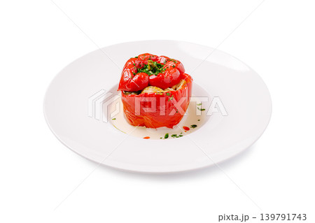 Stuffed red pepper with herbs served on a white plate in a kitchen setting 139791743