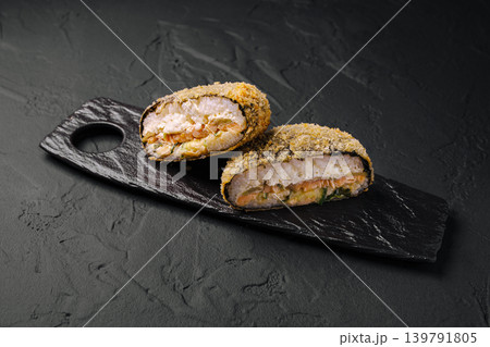 This sushi burger features fried salmon filled with seafood, cut in half to show the filling. This sushi burger features fried salmon filled with seafood, cut in half to show the filling. 139791805