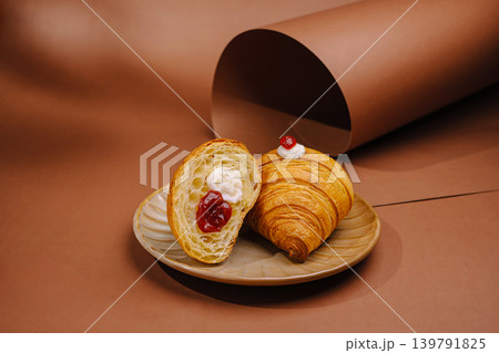 Fresh baked croissant and sweet pastry on a plate in a warm setting Fresh baked croissant and sweet pastry on a plate in a warm setting 139791825
