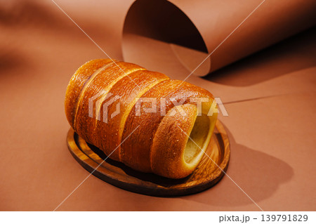 Freshly baked bun displayed on a wooden plate on a brown surface Freshly baked bun displayed on a wooden plate on a brown surface 139791829