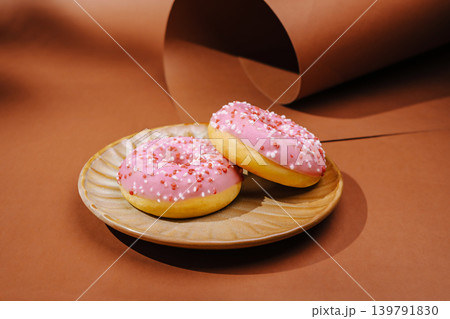 Freshly made donuts on a plate with pink icing and sprinkles Freshly made donuts on a plate with pink icing and sprinkles 139791830