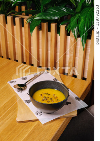 Pumpkin cream soup with seeds in restaurant interior Pumpkin cream soup with seeds in restaurant interior 139792263