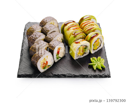 Sushi rolls served on a black plate with wasabi garnish and sauce 139792300