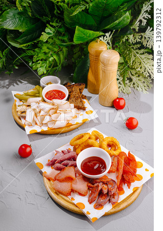 Beer snack platters with lard and smoked sausages served on wooden plates with sauces and vegetables Beer snack platters with lard and smoked sausages served on wooden plates with sauces and vegetables 139792312