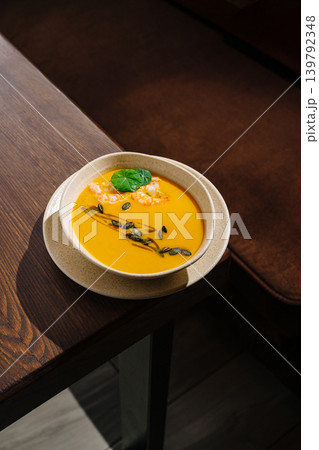 Pumpkin cream soup with shrimps and pumpkin seeds in a cozy setting 139792348