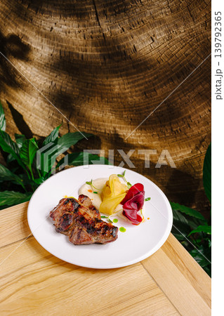 Grilled meat served with colorful vegetables on a wooden table in a garden Grilled meat served with colorful vegetables on a wooden table in a garden 139792365