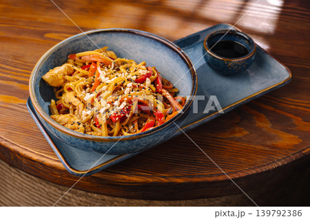 Noodles with chicken and vegetables served in a bowl on wooden table Noodles with chicken and vegetables served in a bowl on wooden table 139792386