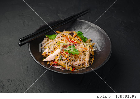 Noodle dish served in a bowl with chopsticks on a dark surface Noodle dish served in a bowl with chopsticks on a dark surface 139792398