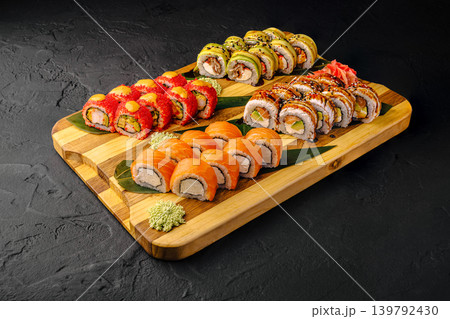 Variety of sushi rolls arranged on a wooden board in a restaurant setting 139792430