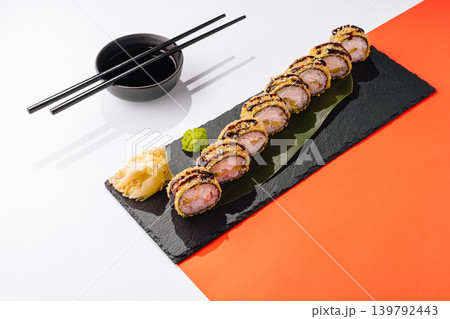 Baked tempura sushi rolls served on a slate plate with chopsticks and sauces nearby Baked tempura sushi rolls served on a slate plate with chopsticks and sauces nearby 139792443