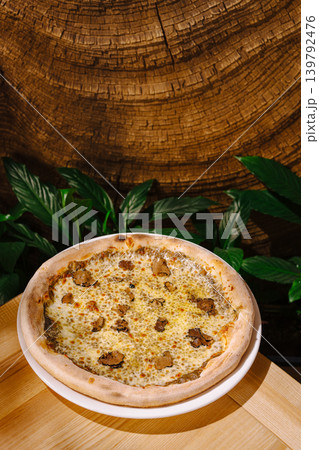 Delicious pizza served on a wooden table with plants in the background Delicious pizza served on a wooden table with plants in the background 139792476