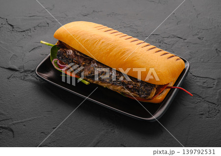 Grilled fish sandwich with vegetables on black plate Grilled fish sandwich with vegetables on black plate 139792531