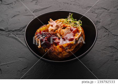 Baked potato with meat and sauce served in black bowl 139792533