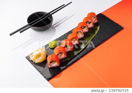 Sushi rolls on a black plate with wasabi and ginger on a white background Sushi rolls on a black plate with wasabi and ginger on a white background 139792535