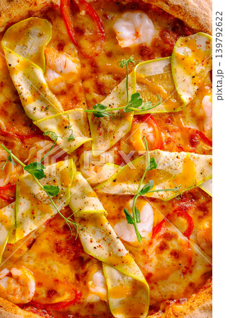 Fresh pizza topped with shrimp and vegetables on a wooden table in a kitchen 139792622