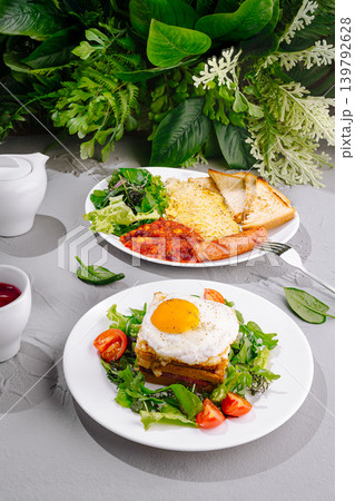 Breakfast plates with eggs, greens, and sausages on table with plants Breakfast plates with eggs, greens, and sausages on table with plants 139792628