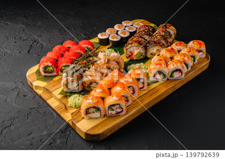 Large sushi set assortment on wooden board at a restaurant in the evening Large sushi set assortment on wooden board at a restaurant in the evening 139792639