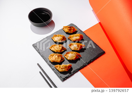Fried gyoza dumplings on slate board with sauce on a clean surface Fried gyoza dumplings on slate board with sauce on a clean surface 139792657