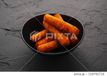 Crunchy fried snacks served in a black bowl on a dark surface Crunchy fried snacks served in a black bowl on a dark surface 139792716