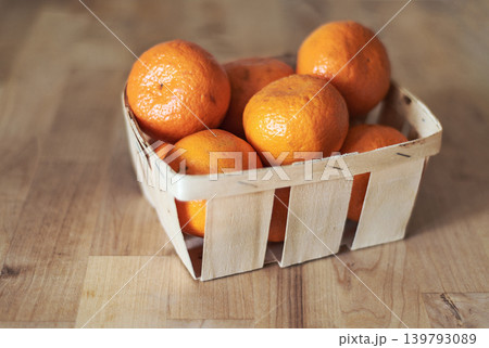 Mandarines in a basket on wooden surface Mandarines in a basket on wooden surface 139793089