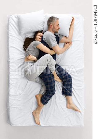 Couple sleeping back to back on white bed in quiet relationship scene. Couple sleeping back to back on white bed in quiet relationship scene. 139794913