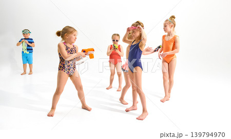 Kids playing with toy water guns and goggles on white studio background. 139794970