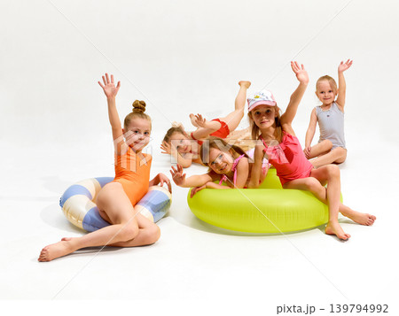 Smiling girls waving from inflatable pool floats on white studio background. 139794992