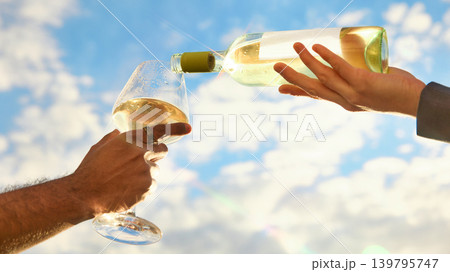White wine pouring into glass against bright blue summer sky White wine pouring into glass against bright blue summer sky 139795747