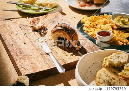 Partly eaten pastry, chips and bread on rustic table after shared snack meal. Partly eaten pastry, chips and bread on rustic table after shared snack meal. 139795769