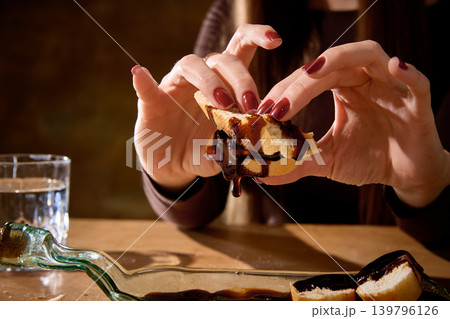 Woman holding bread covered with glossy chocolate sauce in moody food closeup. Woman holding bread covered with glossy chocolate sauce in moody food closeup. 139796126