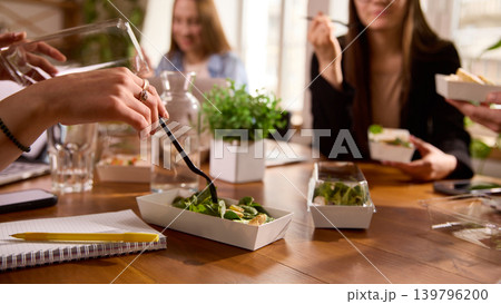 Office workers eating salads together during lunch break. 139796200