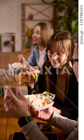 Coworkers eating delivered lunches together during office break. 139796201