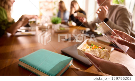 Office worker opening delivered lunch box at wooden conference table. 139796202