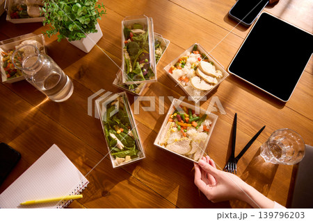 Delivered office lunches with chicken rice and salads on wooden meeting table. Delivered office lunches with chicken rice and salads on wooden meeting table. 139796203