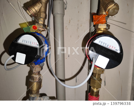 Water Meters with Digital Display and Security Seals. Cold and hot water meter equipped with electronic modules, wire seals, and brass plumbing pipes to measure consumption. 139796338
