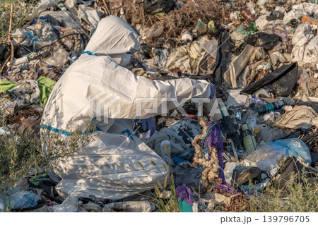 A person in a white hazmat suit is analyzing waste at a landfill, focusing on pollution and its effects on the ecosystem A person in a white hazmat suit is analyzing waste at a landfill, focusing on pollution and its effects on the ecosystem 139796705