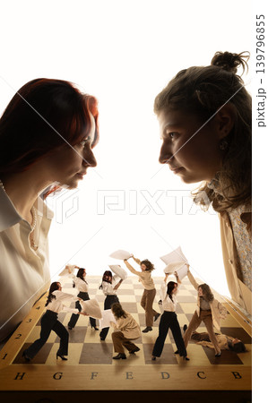 Giant female executives watching miniature office conflict on chess board. Giant female executives watching miniature office conflict on chess board. 139796855