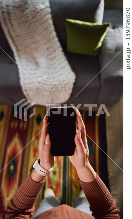 Woman holding smartphone over patterned rug at home from first person view. Woman holding smartphone over patterned rug at home from first person view. 139796870