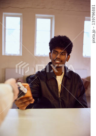 Man paying with smartphone at counter during contactless transaction. Man paying with smartphone at counter during contactless transaction. 139796881