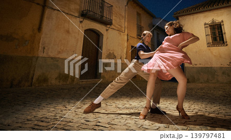Lindy hop dance couple performing on night street with warm light vintage romance energy 139797481