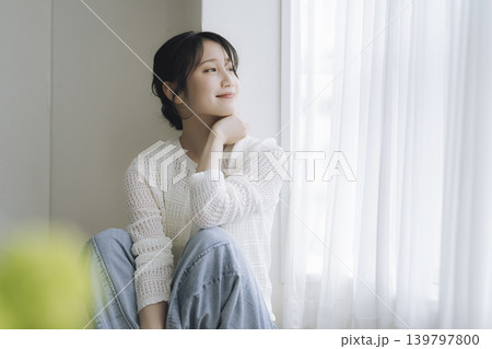 窓辺に座って微笑む若い女性 139797800