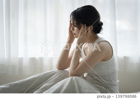 ベッドに座って頭を抱える若い女性 ベッドに座って頭を抱える若い女性 139798086