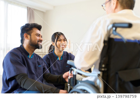 車椅子に座るシニアを見守る外国人介護士 車椅子に座るシニアを見守る外国人介護士 139798759