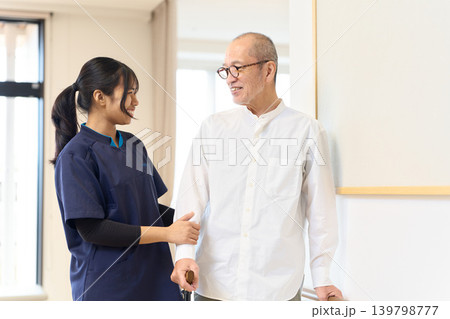 手すりと杖を使って歩く練習をするシニアと外国人介護士 手すりと杖を使って歩く練習をするシニアと外国人介護士 139798777