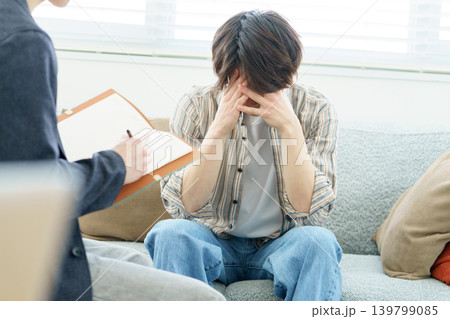 ソファに座ってカウンセリングを受ける若い日本人男性 139799085