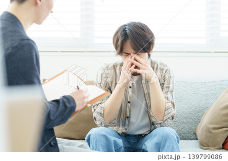 ソファに座ってカウンセリングを受ける若い日本人男性 ソファに座ってカウンセリングを受ける若い日本人男性 139799086
