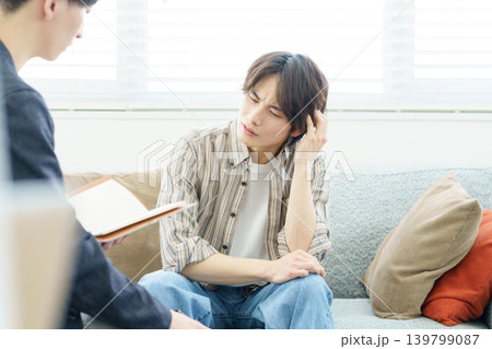 ソファに座ってカウンセリングを受ける若い日本人男性 ソファに座ってカウンセリングを受ける若い日本人男性 139799087