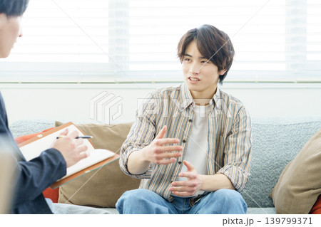 ソファに座ってカウンセリングを受ける若い日本人男性 139799371