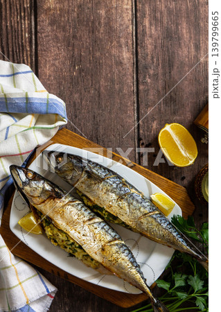 Grilled baked mackerel in ginger mustard honey sauce stuffed with vegetables and cheese on a rustic tabletop. View from above. Copy space. Grilled baked mackerel in ginger mustard honey sauce stuffed with vegetables and cheese on a rustic tabletop. View from above. Copy space. 139799665