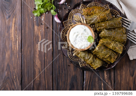Delicious dolma (sarma), dolmades stuffed grape leaves rice, white yogurt sauce. Mediterranean Dolma. Lebanon turkish greek middle eastern cuisine. View from above. Copy space. Delicious dolma (sarma), dolmades stuffed grape leaves rice, white yogurt sauce. Mediterranean Dolma. Lebanon turkish greek middle eastern cuisine. View from above. Copy space. 139799686